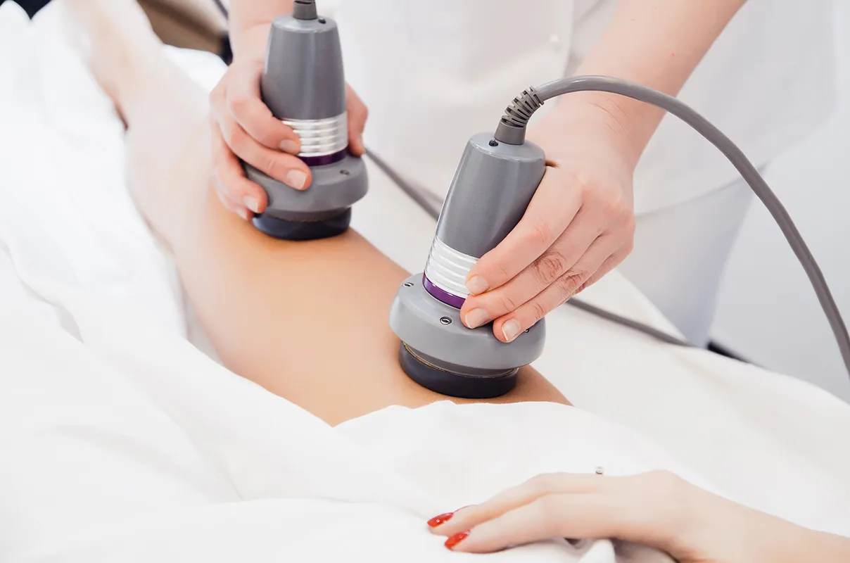 Close-up of a leg treatment using two gray handheld devices.
