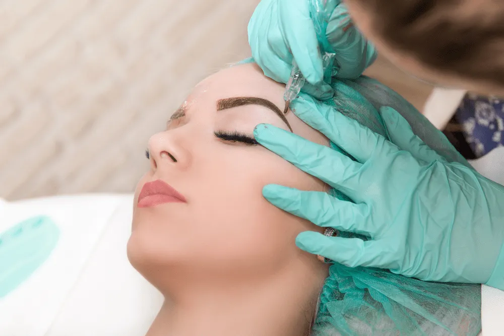 Close-up of microblading procedure on a woman’s eyebrow.
