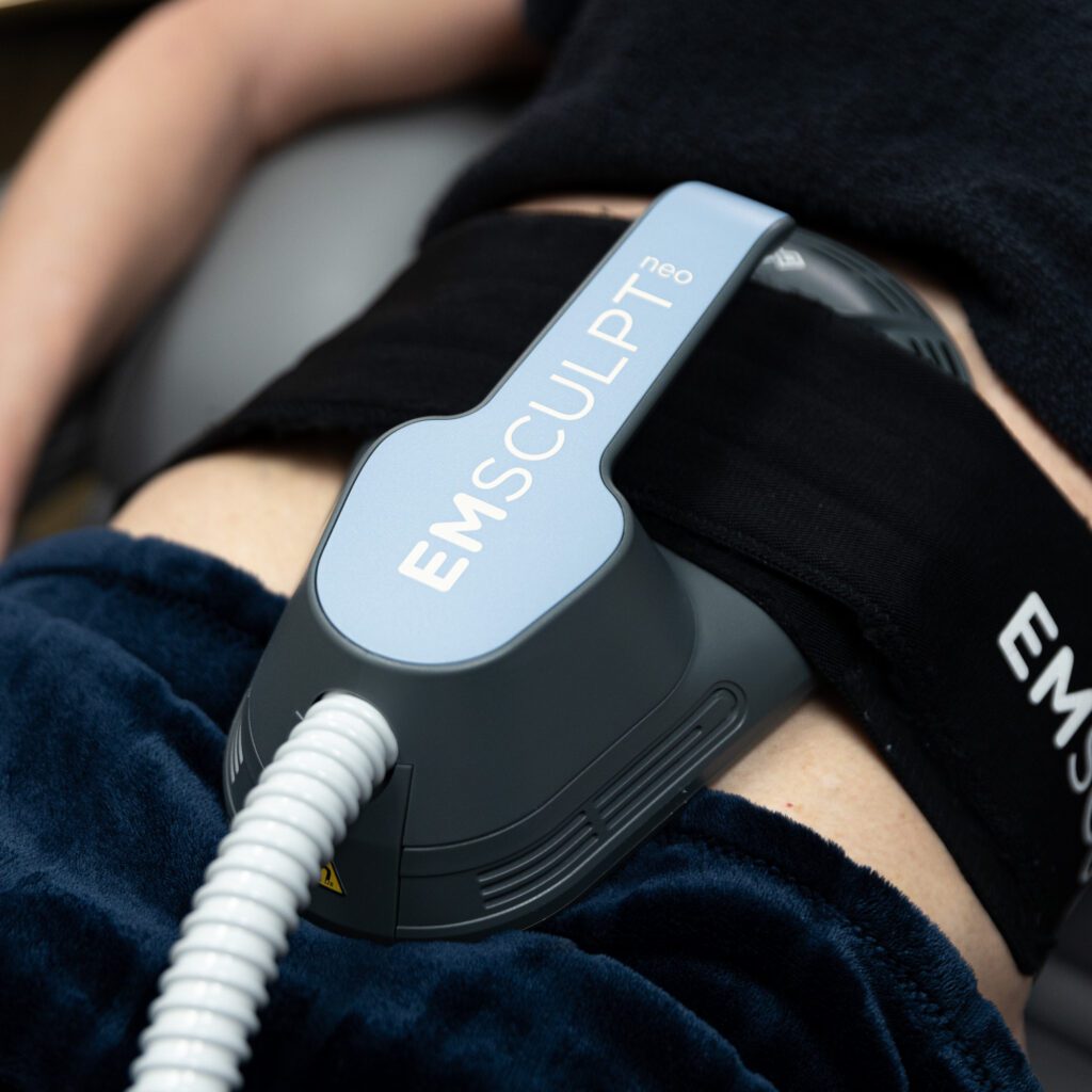 Woman receiving EmSculpt NEO treatment with applicator around midsection at Xanadu Med Spa in Fort Collins, Colorado.