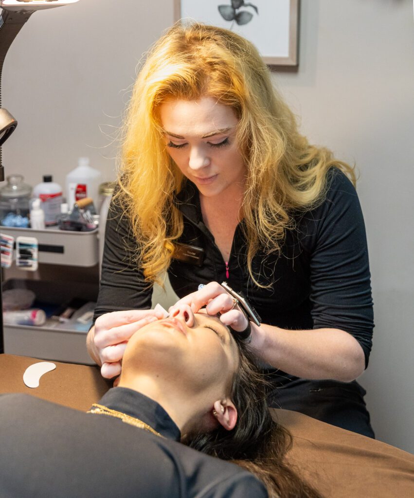 Aesthetician performing facial treatment on client.