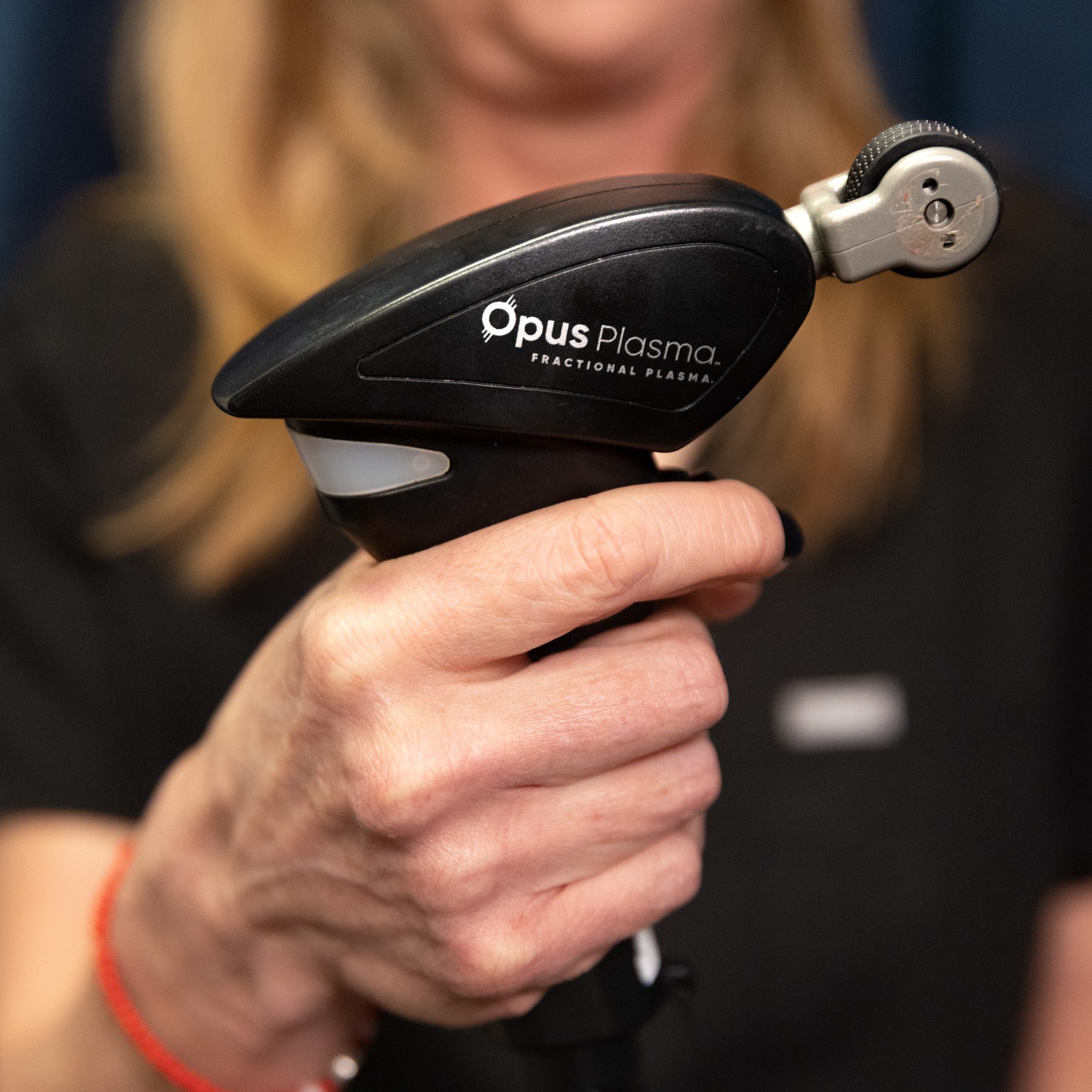 Close-up of a hand holding an Opus Plasma skin treatment device.