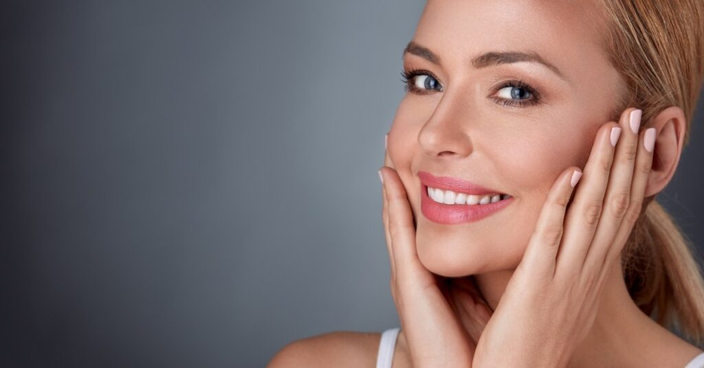 Smiling woman touching smooth glowing skin