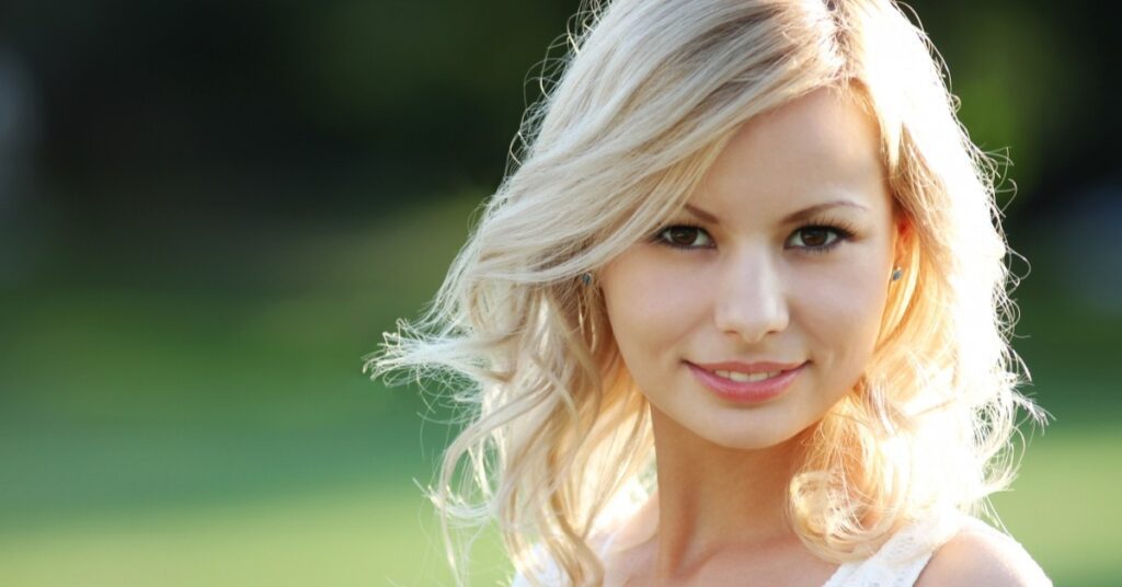 Smiling blonde woman with clear skin in natural sunlight
