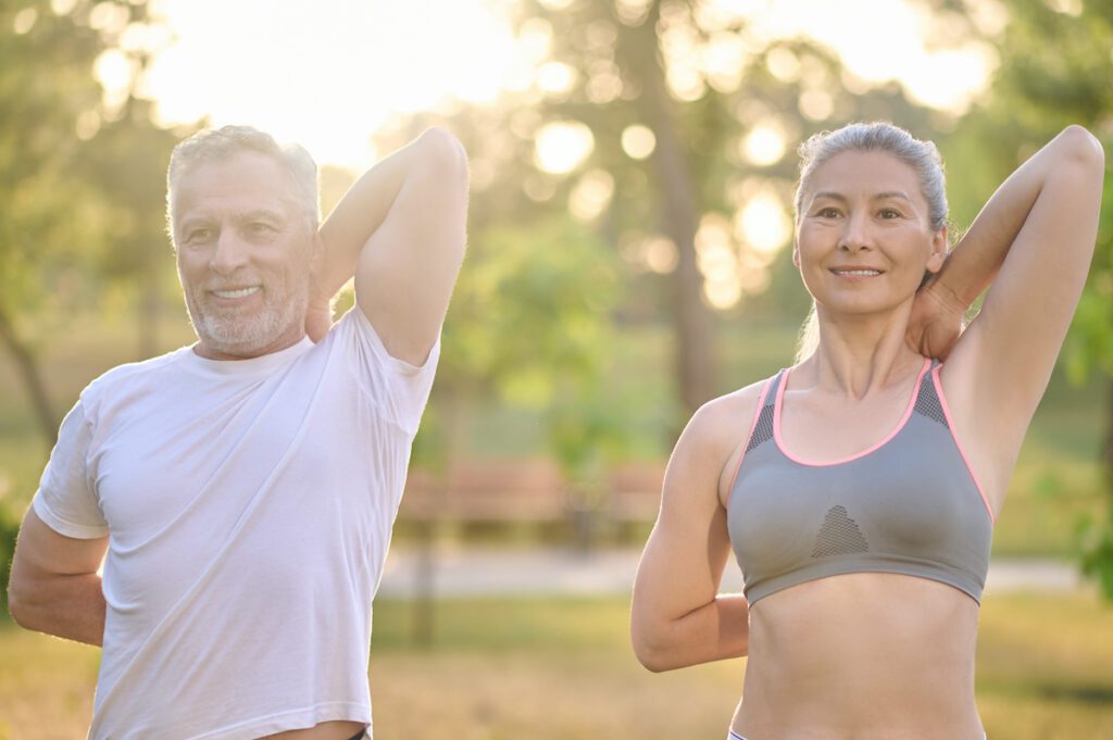 A mid aged couple stretching their enhanced muscles and body contours after body sculpting in Fort Collins