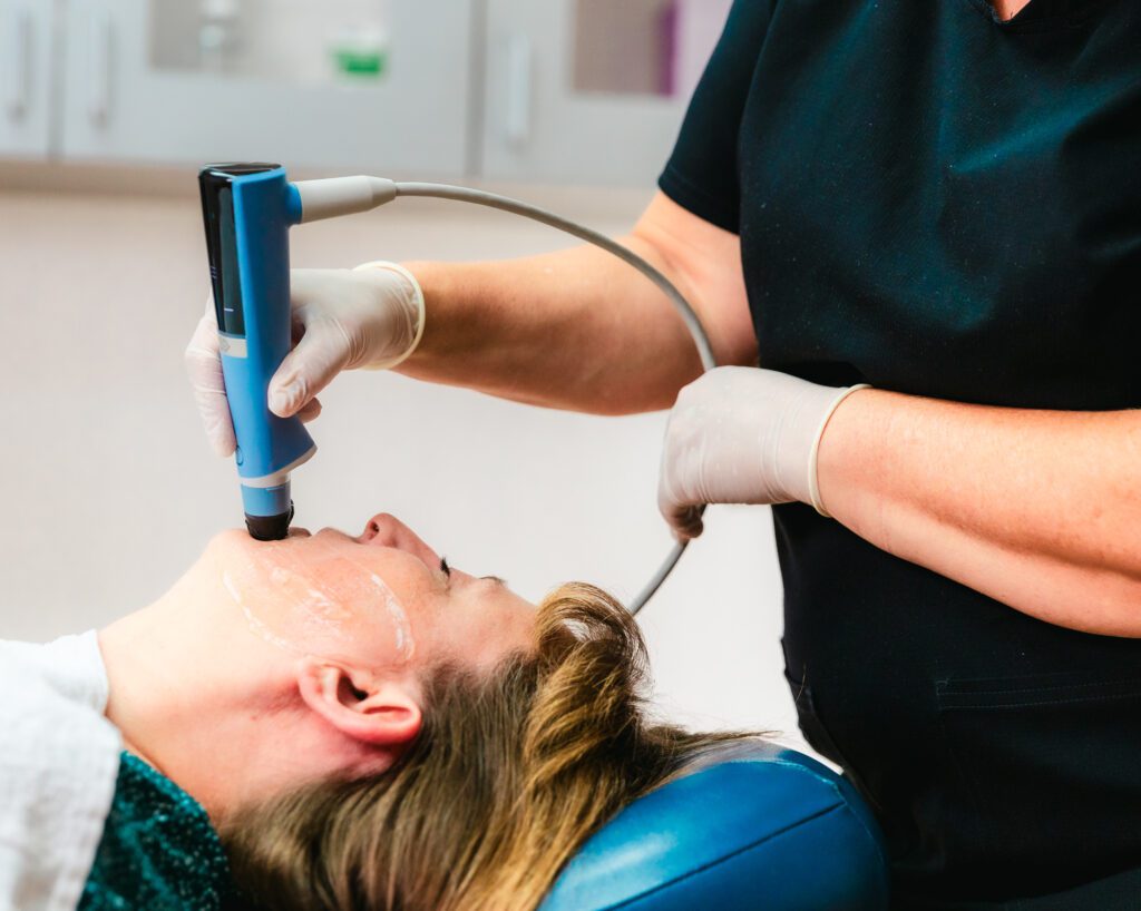 A woman is undergoing treatment with the face applicator for Exion in Fort Collins.