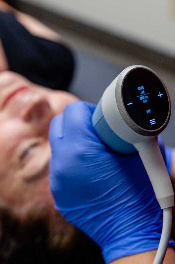 A woman is undergoing treatment with the face applicator for Exion in Fort Collins.